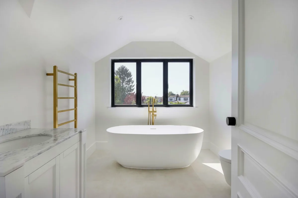 En-suite bathroom with a freestanding bath, marble vanity and brushed-brass fittings