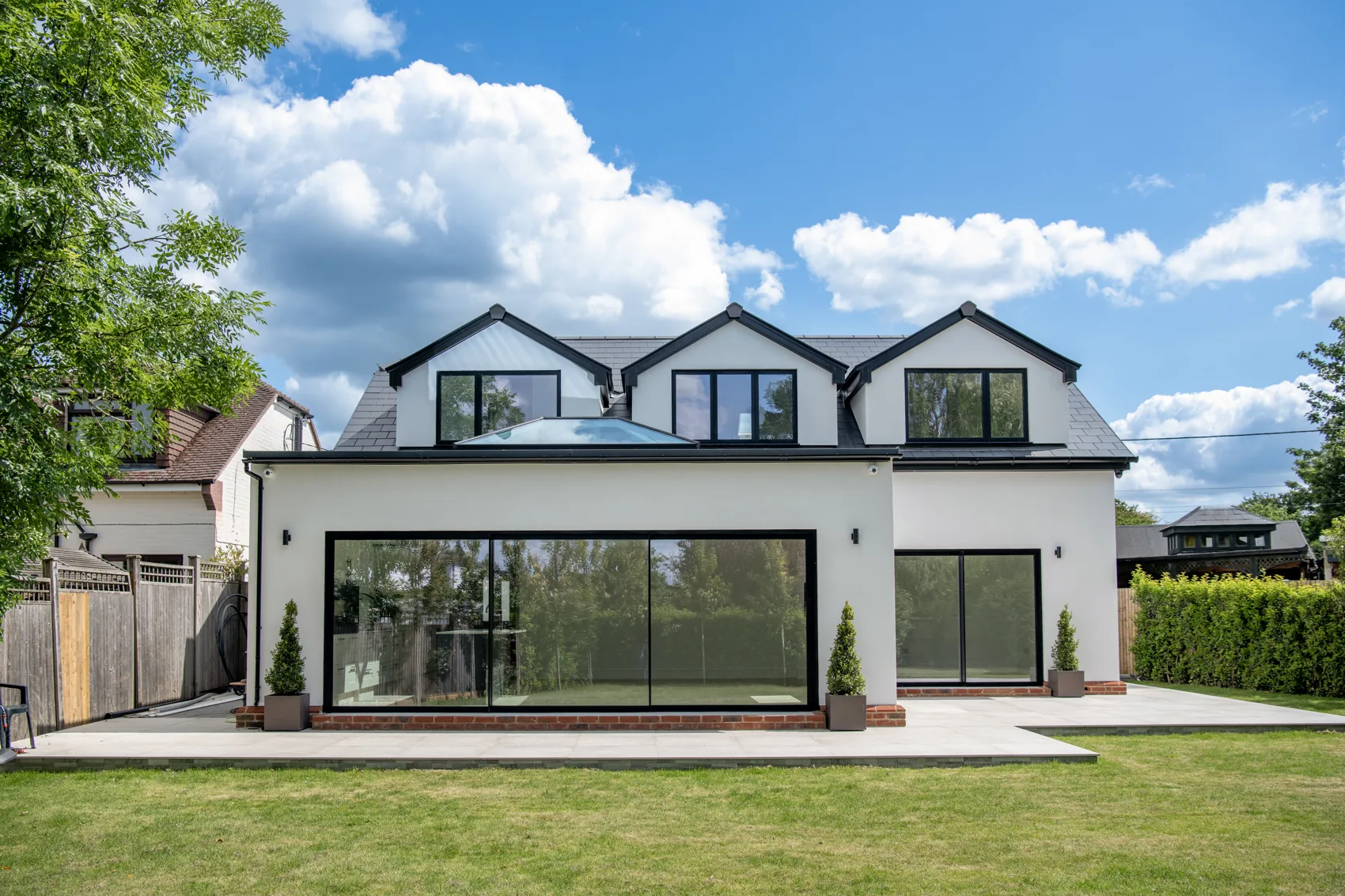 Rear elevation of the development — full-width sliding glazing onto the landscaped garden