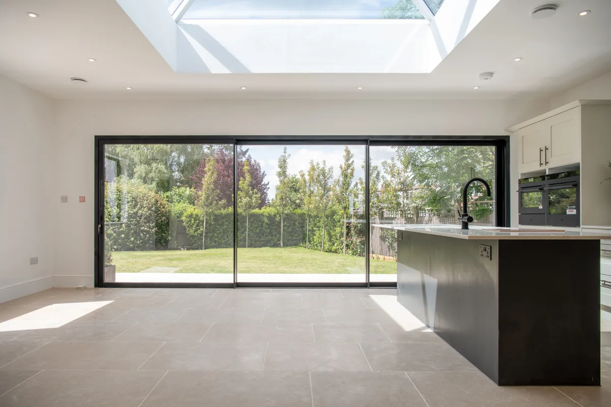 Open-plan kitchen with a roof lantern and full-width sliding doors onto the garden