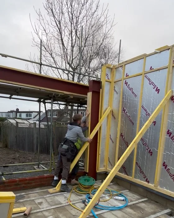 Insulated timber frame panels being braced against the steel on site.