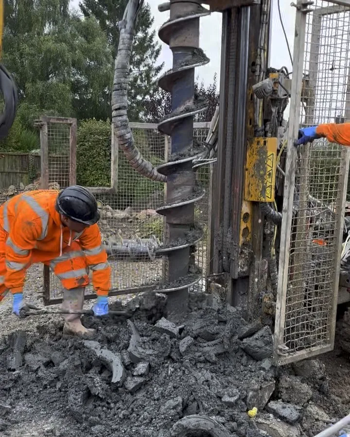 A piling rig augering through clay on site, with the ground crew clearing spoil.